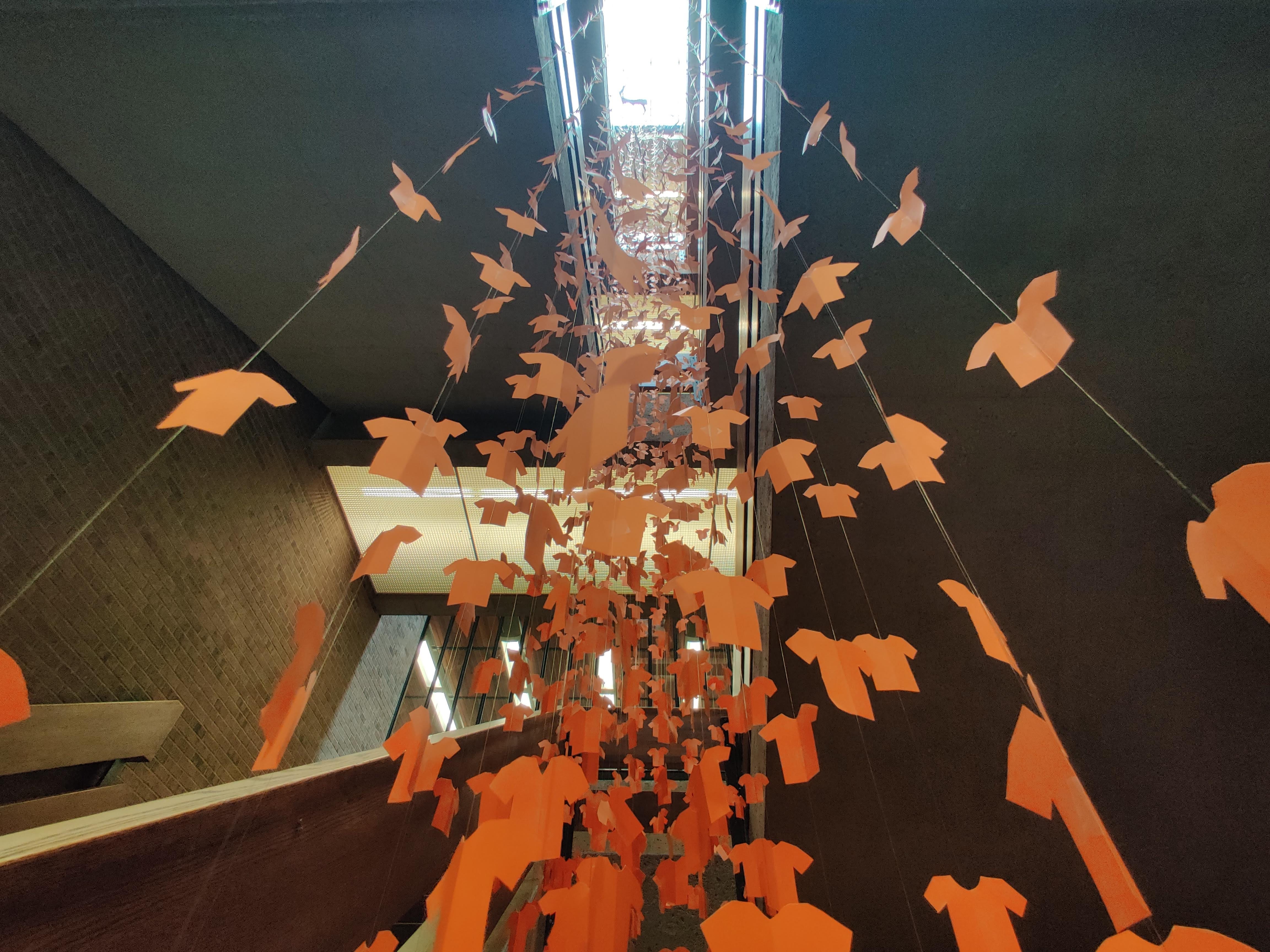 Image of thousands of paper orange shirts hanging from the stairwell at Leddy Library to honour Orange Shirt Day