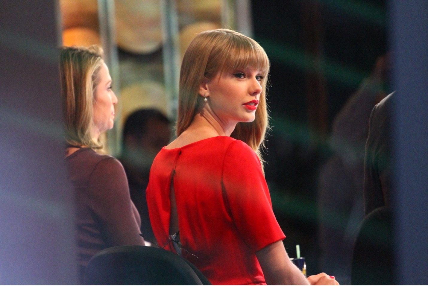A picture of Taylor Swift wearing a red dress, sitting in a chair during an interview