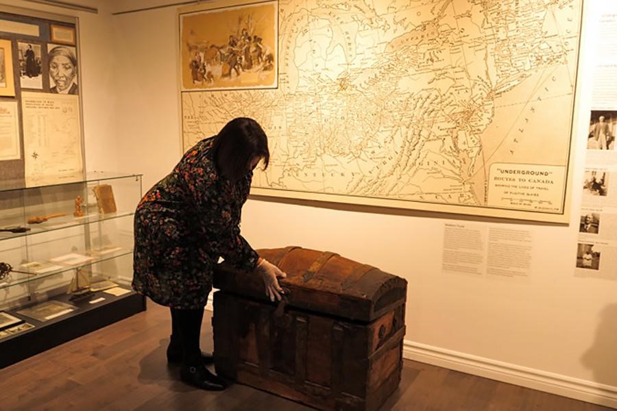 Irene Moore Davis displays an artifact at the Amherstburg Freedom Museum. Allen Watkins used this trunk to transport his children to freedom.  