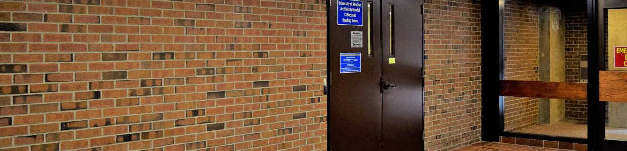 Brick wall and brown metal door with blue signs for Archives and Special Collections