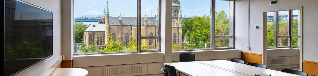 Bright meeting room with large windows overlooking the historic Assumption Church and surrounding campus.