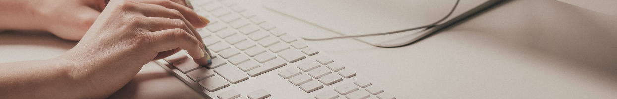 White person's hands typing on white keyboard.