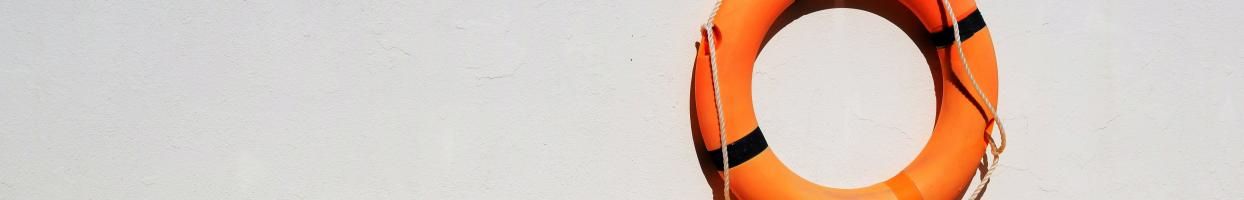 Photo of an orange buoy hanging on a white wall. 