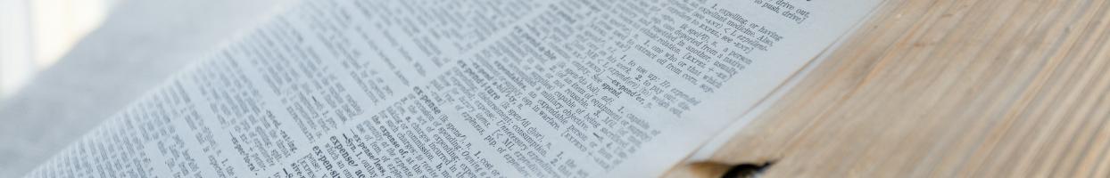 Photo of an open dictionary with white pages and black type.