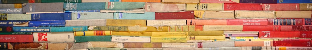 Photo of colorful books stacked on top of each other with their spines visible. 