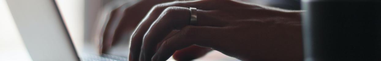 Photo of hands typing on keyboard of laptop.