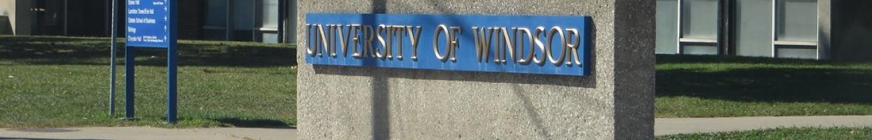 Photo of University of Windsor sign in blue on concrete. 