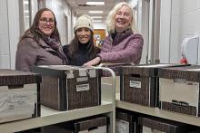 Sarah Glassford, Emmanuelle Richez and Katharine Ball pose with boxes of the Le Rempart donation